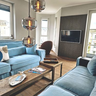 Wohnzimmer mit hellblauer Sitzecke und Fernseher